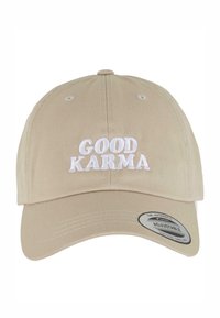 Beige állítható baseballsapka, elöl fehér hímzett felirattal: "GOOD KARMA", és ezüst szalaggal a karimáján.