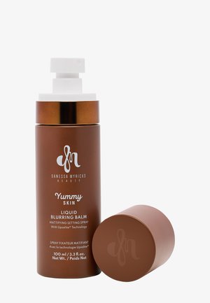 Brun cylindrisk behållare med en vit spraymunstycke, märkt "Yummy Skin Liquid Blurring Balm." Inkluderar en matchande, rund brun kork.