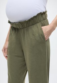 Ελαφριά παντελόνια εγκυμοσύνης σε ελιά πράσινο χρώμα με βολάν στη μέση και πλαϊνές τσέπες. Κατασκευασμένα από απαλό, υφήρικο ύφασμα για άνεση.