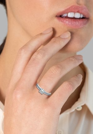 Platinring mit einem zentralen quadratischen Diamanten und seitlichen Akzenten aus kleineren Diamanten. Glatte Band mit polierter Oberfläche.