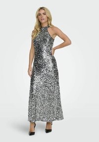 Robe maxi en sequins noirs et argentés avec un design à encolure halter. La robe présente un corsage ajusté et un bas évasé.