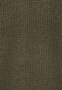 Texturovaná látka v tmavě olivově zelené barvě, s pleteným vzorem, viditelnými stehy a mírnými variacemi v odstínech. Měkký a přívětivý povrch.