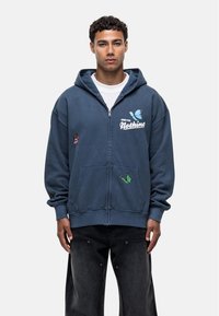 Blue zip-up hoodie made of soft fabric with two front pockets, featuring colorful butterfly embroidery and a logo print on the chest.