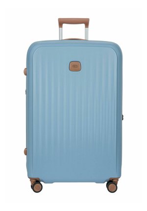 Valigia rigida azzurro chiaro con manico marrone, quattro ruote girevoli nere e marroni e scanalature verticali testurizzate.