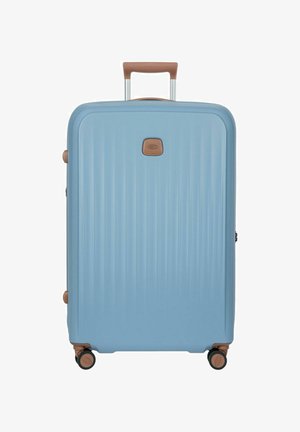 Valigia rigida azzurro chiaro con manico marrone, quattro ruote girevoli nere e marroni e scanalature verticali testurizzate.
