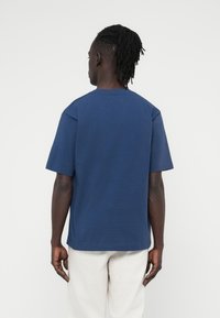 Μπλε ναυτικό T-shirt με κοντό μανίκι από βαμβάκι, με άνετη γραμμή και μινιμαλιστικό σχεδιασμό. Ομαλή υφή με στρογγυλή λαιμόκοψη.