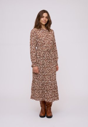 Bruine bloemen lange mouwen jurk met een tailleband, uitlopende rok en geplooide manžetten; gedragen met bruin leren kniehoge laarzen.