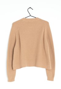 Beige gebreide trui met een ribbelstructuur, ronde halslijn en raglanmouwen. Het heeft een relaxte pasvorm en een subtiel gebogen zoom.