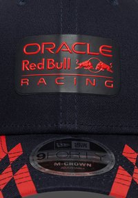 Μπλε καπέλο με ανάγλυφο μαύρο σήμα που γράφει "ORACLE Red Bull RACING" με κόκκινα γράμματα και γραφικό κόκκινο ταύρο. Περιλαμβάνει αυτοκόλλητο New Era 9FORTY.