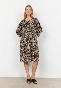 Leopardskinnad klänning i beige och svart, med en lös passform, V-ringning och trekvartslånga ärmar. Bärs ihop med svarta klacksandaler.