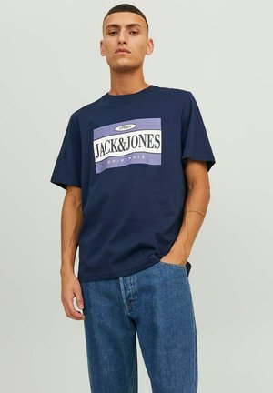Camiseta de algodón color marino con un gran estampado en blanco y morado del logo "JACK & JONES ORIGINALS" en el frente, corte relajado y cuello redondo.