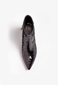 Stivale alla caviglia nero con paillettes, punta affusolata, chiusura con cerniera e superficie testurizzata. Presenta una soletta imbottita con il logo del marchio all'interno.
