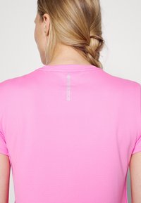 Pink athletic t-shirt featuring a ribbed texture and short sleeves. Logo detail is visible on the back near the neckline.