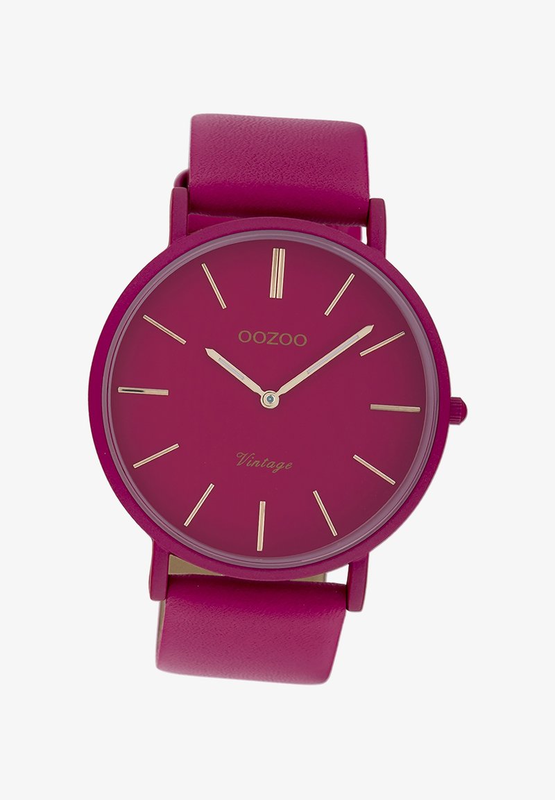 Montre ronde avec un bracelet en cuir fuchsia et un cadran fuchsia assorti. Index et aiguilles dorés. "Oozoo Vintage" imprimé sur le cadran.