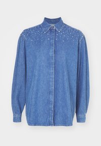 Denim shirt in blue, featuring a button-up front, collar, and puffed sleeves. Sturdy fabric with clear embellishments on shoulders.