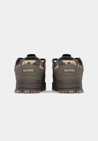 Dark green sneakers with a camo-patterned heel and accents. Includes prominent brand logo and textured rubber sole for grip.