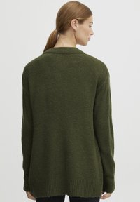 Gilet en maille vert olive avec une coupe décontractée, ourlet côtelé et col châle, présentant une texture douce et des manches longues.
