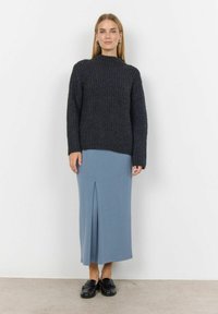 Donkergrijze geribde trui met hoge hals; gecombineerd met een lichtblauwe midi rok met een split aan de voorkant. Zwarte loafers maken de outfit compleet.