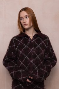 Suéter burdeos con un patrón de textura suave y esponjosa, que presenta un diseño de diamantes y un cuello con solapa. Se pueden ver botones grandes.