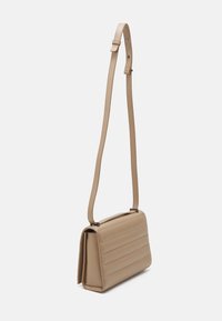 Beżowa syntetyczna torebka crossbody z pikowanym wzorem, regulowanym paskiem i eleganckim prostokątnym kształtem. Gładka tekstura z minimalną ilością elementów metalowych.