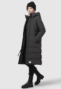 Black long puffer coat with a hood, horizontal quilted design, two zippered pockets, paired with black fitted pants and ankle boots.