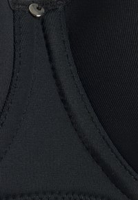 Svart behå med slät, stretchig tyg och en texturerad yta. Har förstärkt sömnad och metallisk spänne.