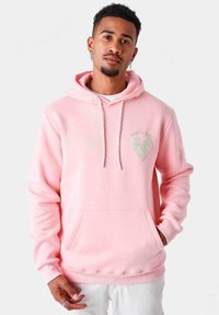 Hoodie rosa chiaro realizzato in morbido tessuto, dotato di tasca frontale, cappuccio con coulisse e dettaglio ricamato a forma di cuore sul petto.