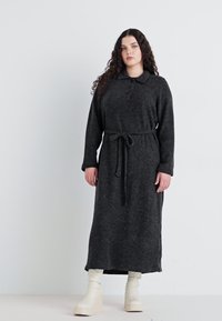 Rochie lungă de culoare gri închis, dintr-un material moale, cu guler, plastron cu nasturi și un cordon la talie. Purtați-o cu botine cu platformă de culoare crem.