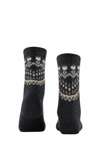 Schwarze Strümpfe aus Wolle mit einem gemusterten Design, das weiße und beige Akzente beinhaltet, einschließlich geometrischer Formen und Motiven im Bereich des Bündchens.