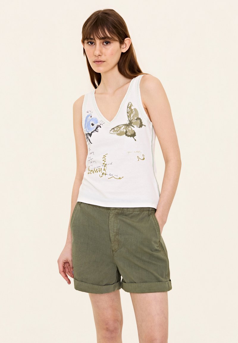 Witte tanktop met blauwe en groene vlinder- en bloemenprints, met een v-hals ontwerp, gecombineerd met olijfgroene opgerolde shorts.