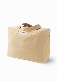 Sac fourre-tout en tissu beige avec double poignées, de forme rectangulaire, fermeture zip sur le dessus et étiquette à l'avant. Texture douce, design minimaliste.