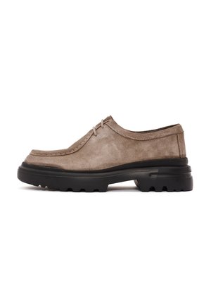 Zapatos de ante gris con punta redondeada, costuras decorativas y suela de goma negra con patrones de agarre texturizados. Diseño de perfil bajo.