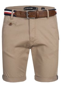 Shorts en kaki avec un ourlet roulé, présentant une ceinture en cuir marron et un accent en tissu rayé rouge, blanc et bleu à la taille.