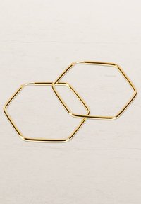 Goldene hexagonale Creolen, glattes Metall mit glänzender Oberfläche, mit offener Gestaltung und markantem geometrischen Format.