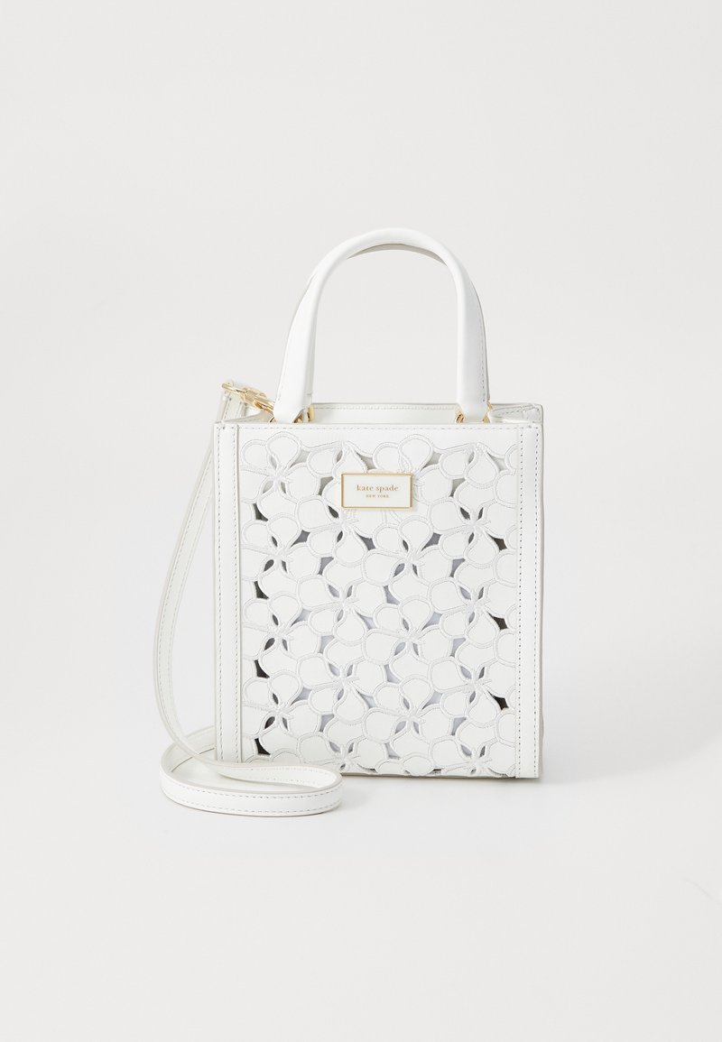 Bolsa de couro branca com padrão floral recortado, ferragens douradas, alças superiores e uma alça de ombro destacável. Mede aproximadamente em formato quadrado.