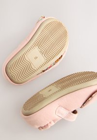 Vaaleanpunaiset kangaslenkkarit, joissa on teksturoitu beige pohja. Sivussa on kukkakuvio, ja ne säätyvät tarranauhalla.