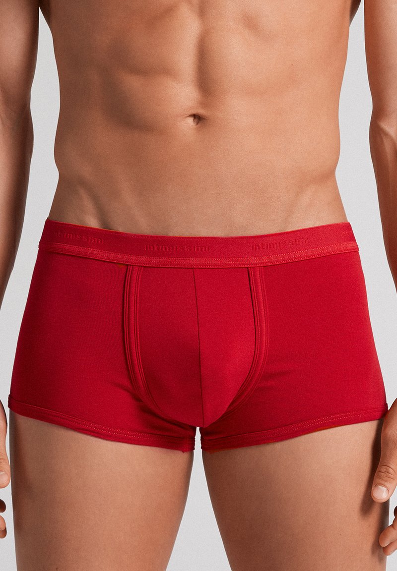Boxer-culottes rouges en tissu lisse. Caractéristiques : coupe ajustée, poche fonctionnelle et ceinture élastique douce avec logo de la marque.
