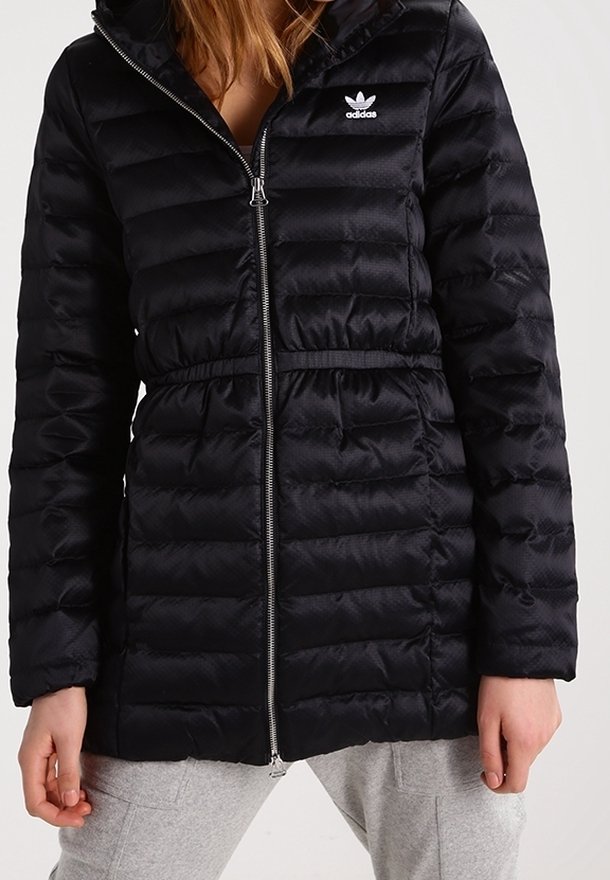 Svart pufferjacka med dragkedja och dragsko i midjan. Har en huva och en liten vit Adidas-logotyp på bröstet, quiltad textur.