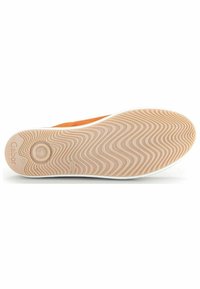 La semelle de la chaussure est en caoutchouc beige texturé avec un motif ondulé, des accents orange sur le dessus, et une bordure blanche autour du bord.