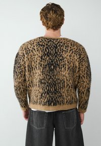 Bruin en zwart gevlekt gebreid sweater met een losse pasvorm en lange mouwen, met een gestructureerd, zacht materiaal en een cropped lengte.