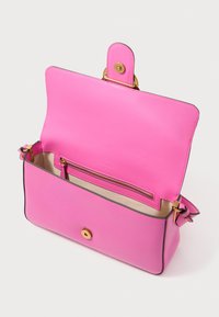 Rózsaszín bőr kézitáska mágneses záródással, arany színű fémrésszel és belső cipzáros zsebbel, sima textúrával és letisztult formával.