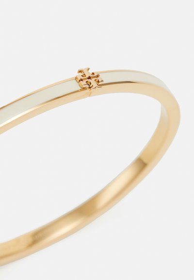 Zlatý náramok s hladkým, lešteným povrchom. Obsahuje jemné zapínanie vo forme puzzle, minimalistický dizajn a elegantný, zaoblený tvar.