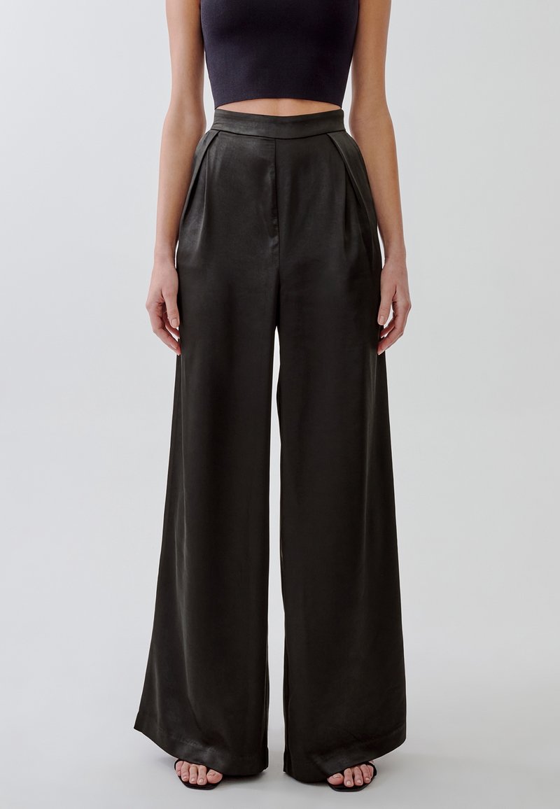 Pantaloni a gamba larga in tessuto scuro con una texture liscia e lucida. Design a vita alta con pieghe e tasche laterali.