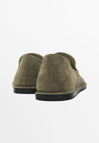Olijfgroene suède instappers met een zachte textuur, ronde hak en zwarte rubberen zool. Voorzien van een gestikte randafwerking.