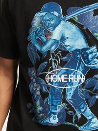 Black t-shirt featuring a blue graphic of a child with a bat amid green and purple plants, text "HOME RUN" in a white oval.