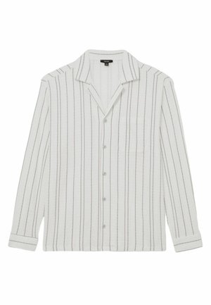 Valkoinen pitkähihainen paita mustuine pystysuorine raidoineen, nappikiinnitys edessä, leveä kaulus ja vasemmalla puolella rinnantasku.