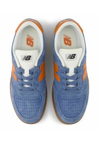 Blue suede sneakers with orange accents, white laces, perforated toe box, and a brown rubber sole. "NB" logo on the tongue and side.