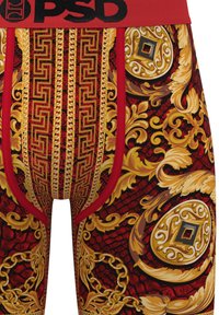 Red boxer briefs featuring ornate gold and black patterns with a chain motif, accented by a black waistband with the brand logo "PSD."
