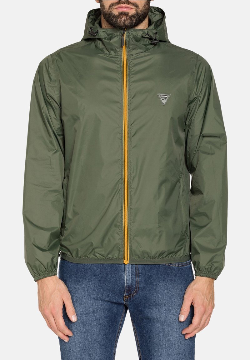 Lätt grön jacka med huva, har en framdragkedja med gula accenter, elastiska ärmslut och ett logotygetikett på bröstet.