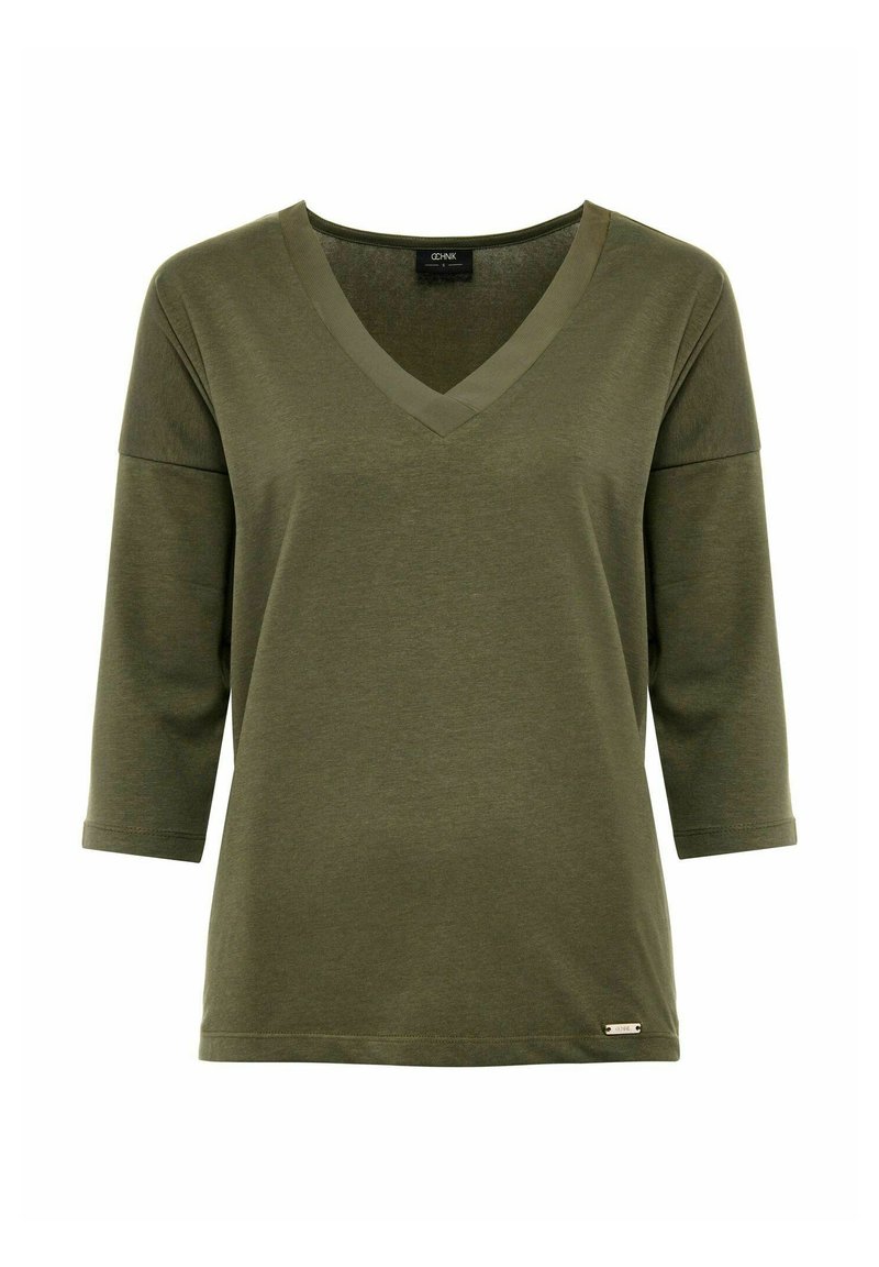 Olijfgroene top met V-hals en driekwartmouwen, gemaakt van een zachte, gladde stof. Heeft een contrasterende halslijn en een klein merklabel aan de zoom.